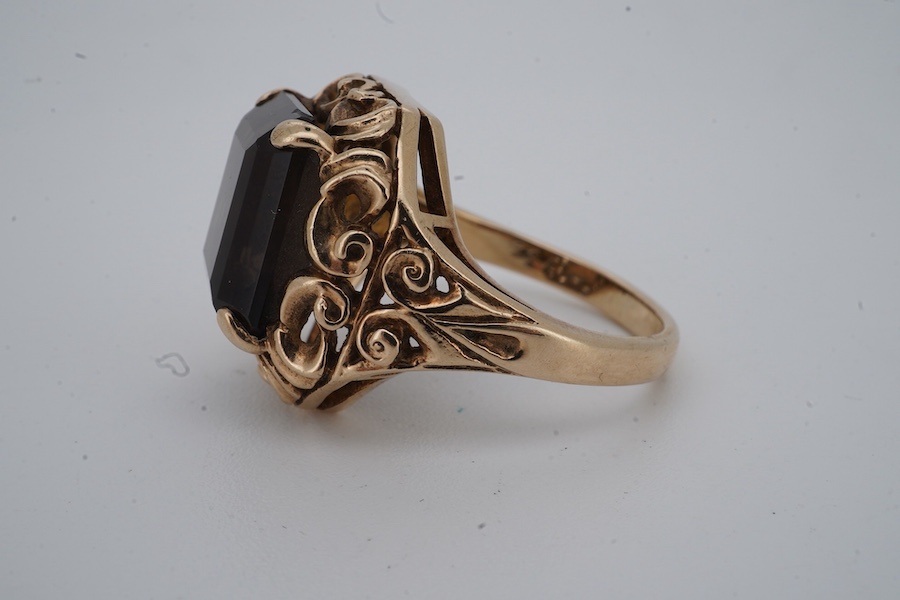 A smoky quartz dress ring, set with a step-cut smoky quartz, to a scrolled mount, size O, stamped PPLd 9CT, numbered, gross weight 6 grams